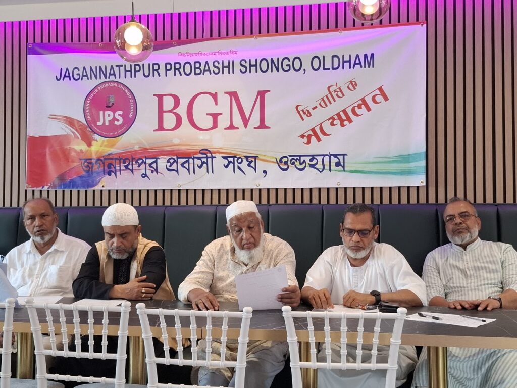 Five committee members seated at the top table beneath the JPS Biennial General Meeting banner, Uzan Vati Restaurant, Oldham.