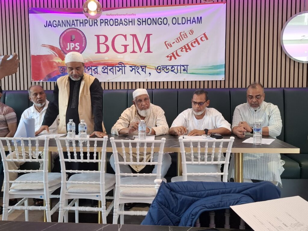 A member stands to address the Biennial General Meeting while others remain seated at the top table.